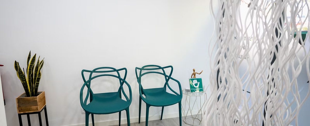 Sala de espera de FES Fisioterapia en Barcelona, con butacas verdes y luz natural